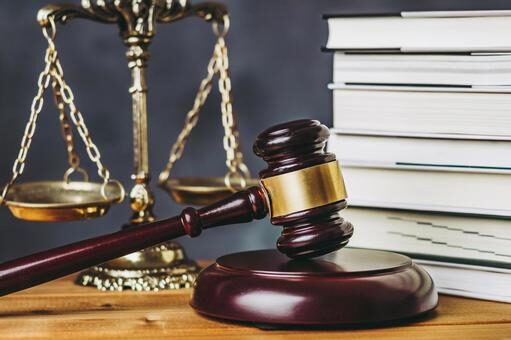 茶色のテーブルの上に金色の天秤が置かれている  
手前右には裁判で使う木槌とゴングセット  
赤茶色でつるつるした質感のハンマーが目立っている。
