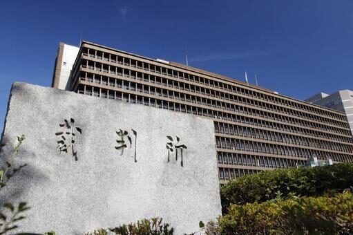 石の看板が正面に大きく写っている  
右側には有名な裁判所の建物がそびえている  
青空が広がり晴れ渡った風景。